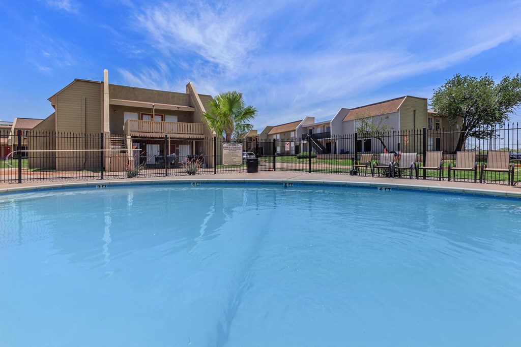 a swimming pool in front of a building with apartments in the background