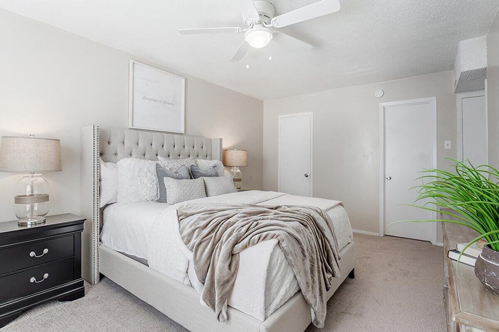 a white bedroom with a bed and a ceiling fan