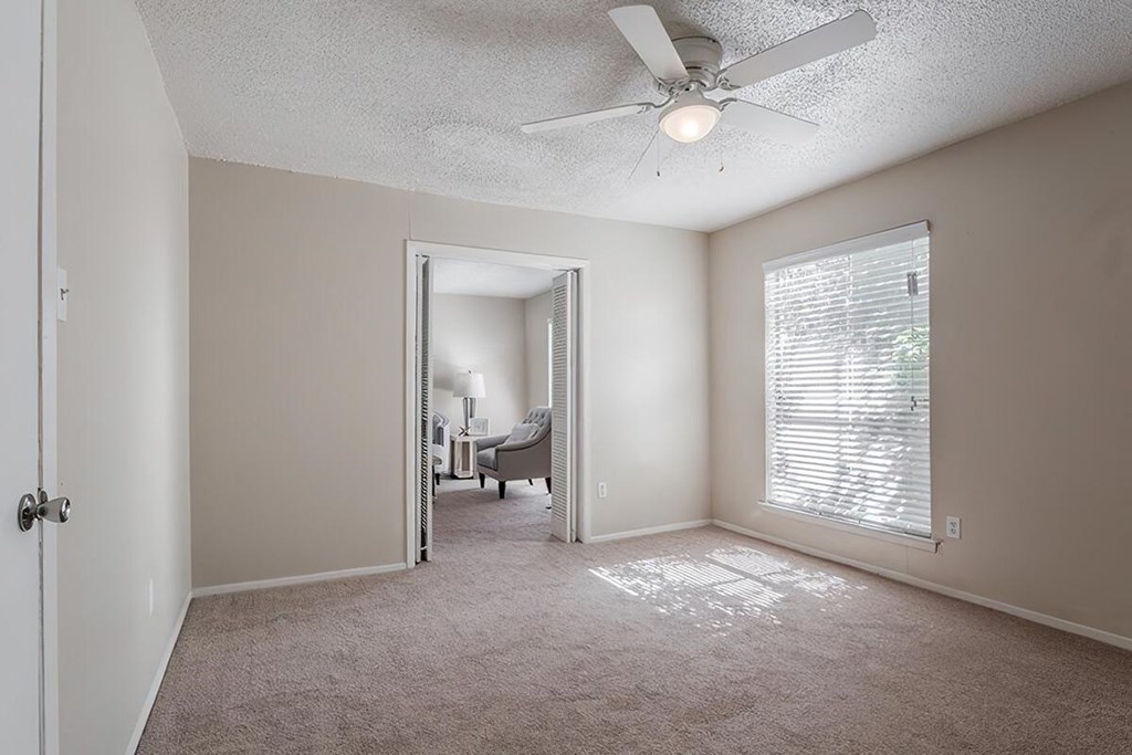 an empty living room with a ceiling fan