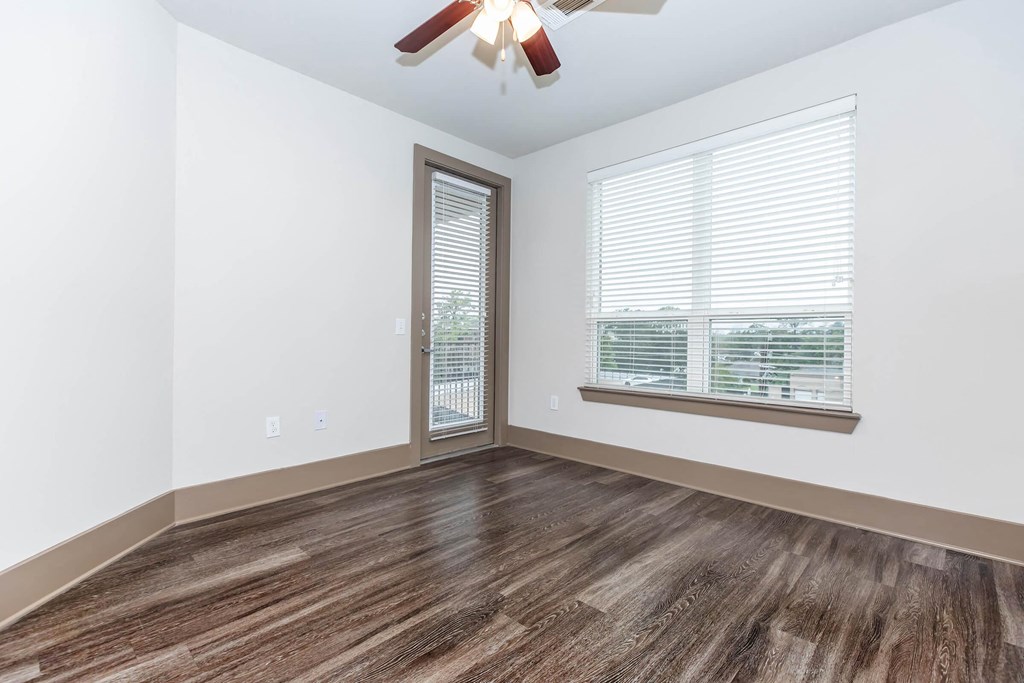 an empty bedroom with a window and a ceiling fan
