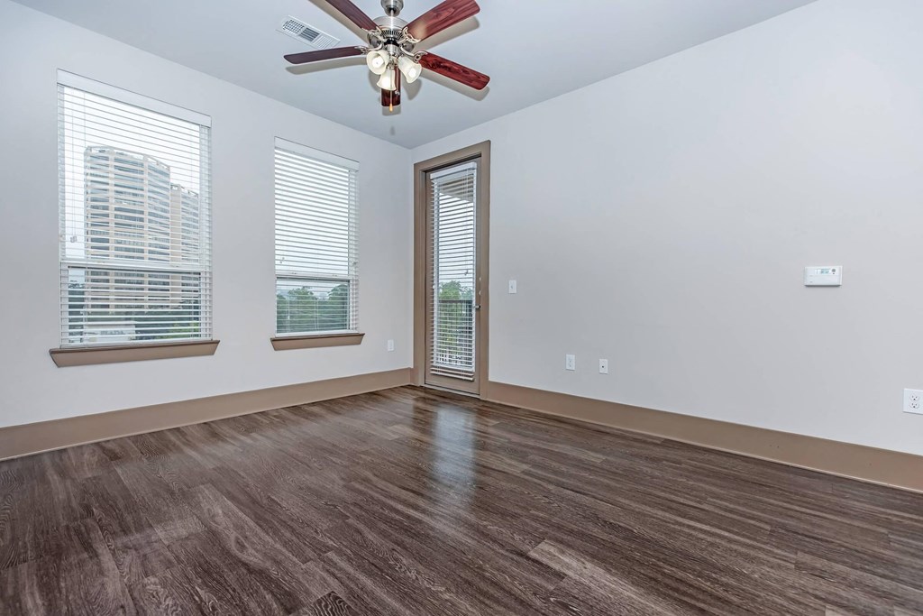 an empty living room with a ceiling fan and windows