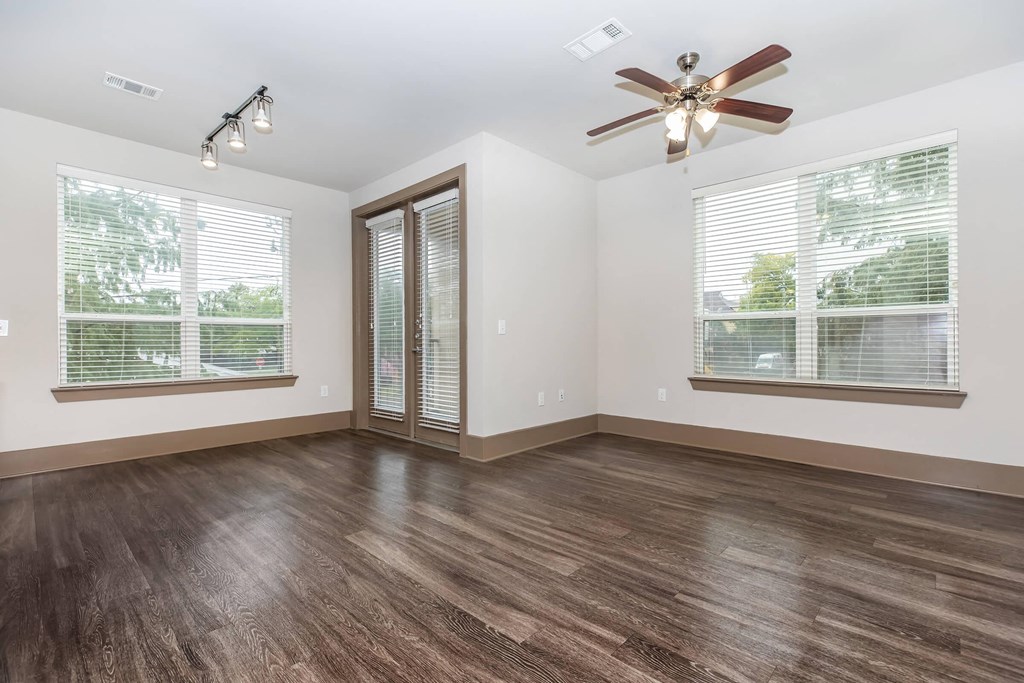 an empty living room with a ceiling fan and two windows