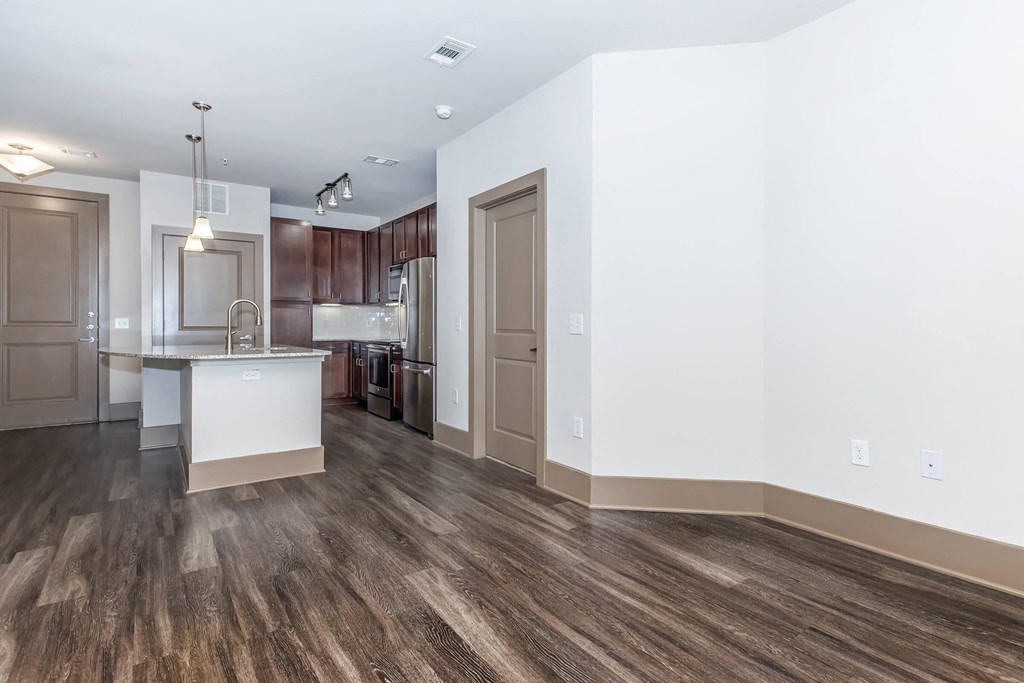 a renovated living room and kitchen with white walls and wood floors