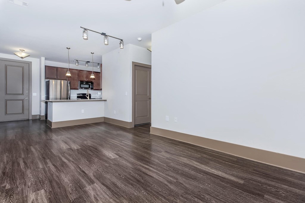 a living room and kitchen with white walls and wood floors