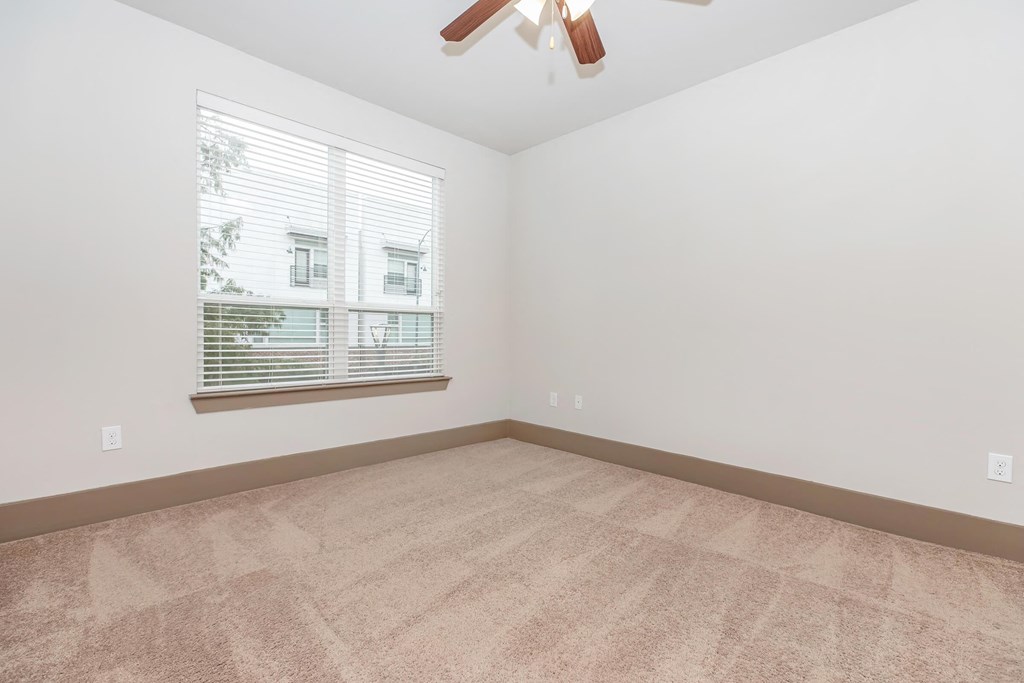 a living room with a large window and carpet