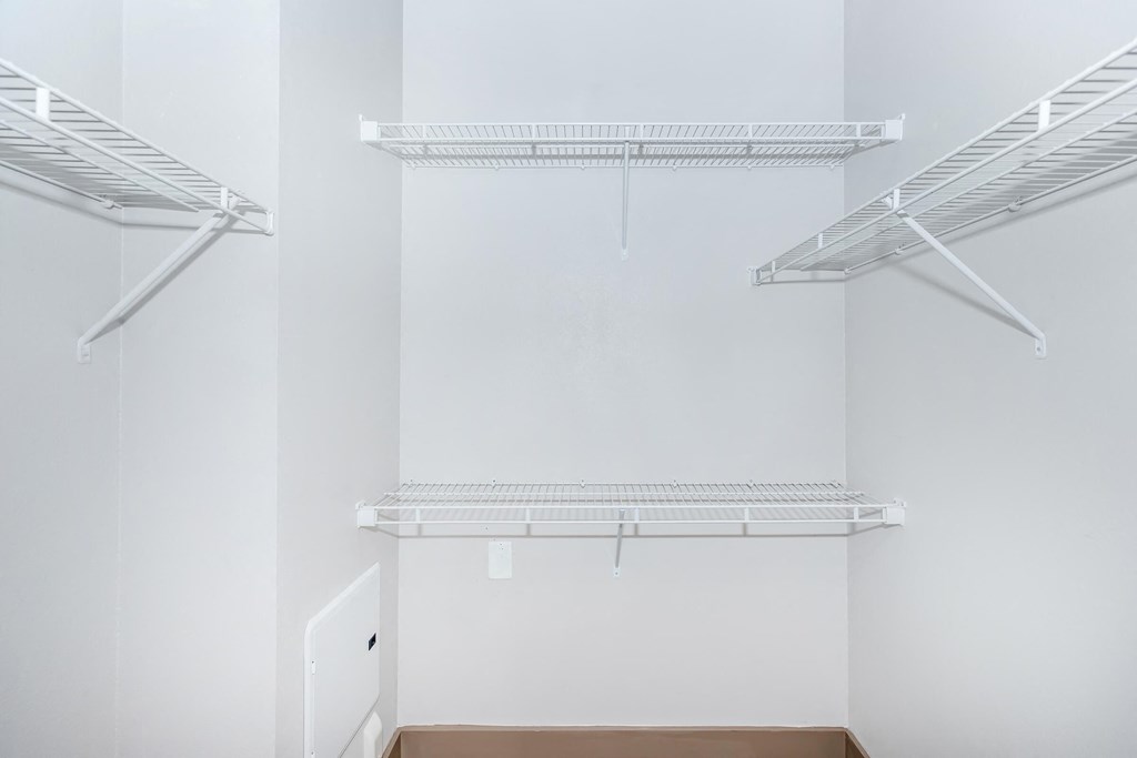 a walk in closet with white walls and white shelves
