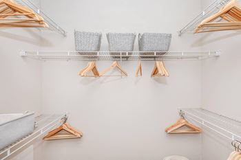 a walk in closet with shelves and clothes racks