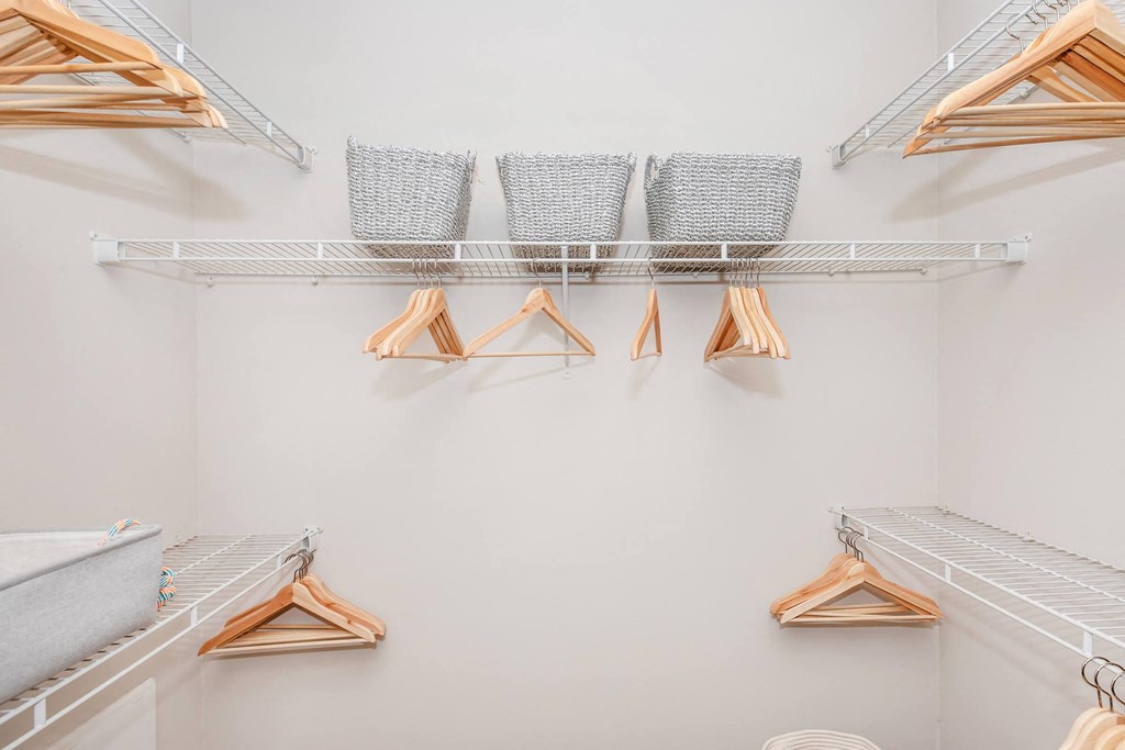 a walk in closet with shelves and clothes racks