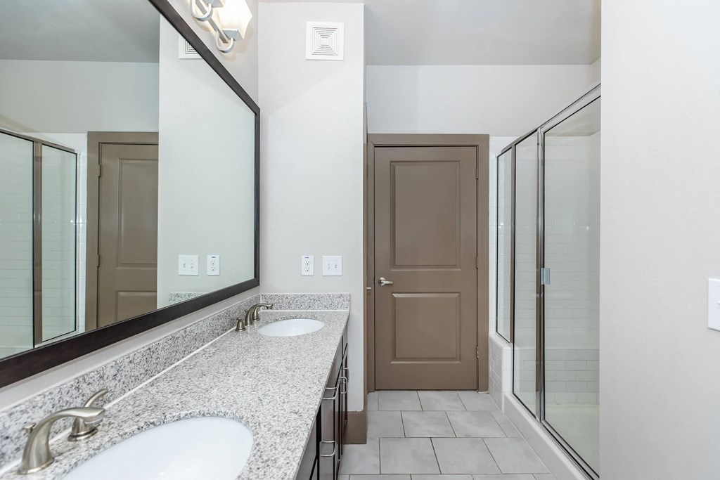 a bathroom with two sinks and a mirror and a shower