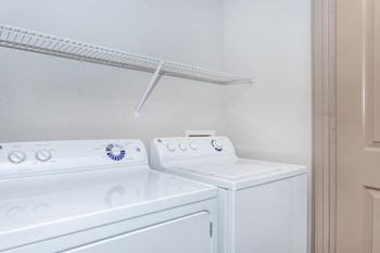a white washer and dryer in a laundry room with a shelf above