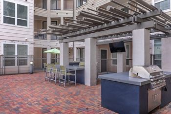 a patio with a grill and a table with chairs