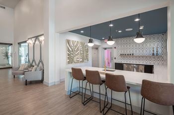 a kitchen with a bar and chairs in front of a living room