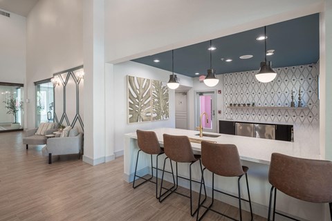 a kitchen with a bar and chairs in front of a living room
