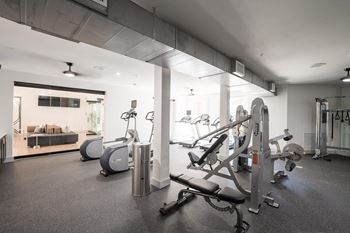 a gym with cardio equipment and a living room with a couch