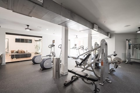 a gym with cardio equipment and a living room with a couch