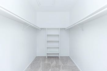 an empty room with white walls and a closet with shelves