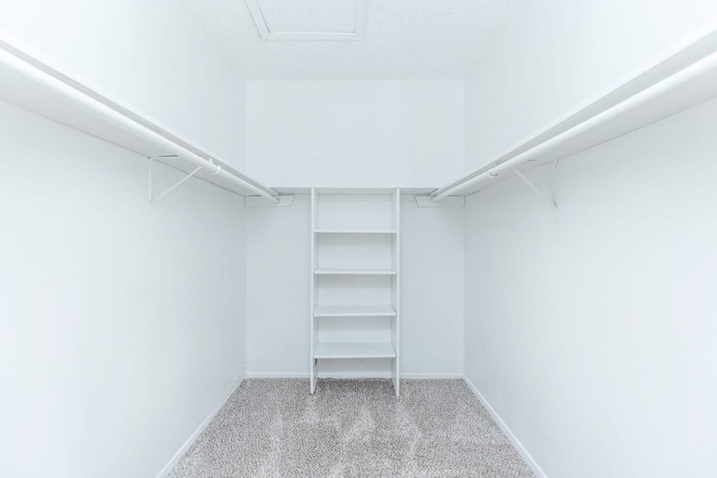 an empty room with white walls and a closet with shelves