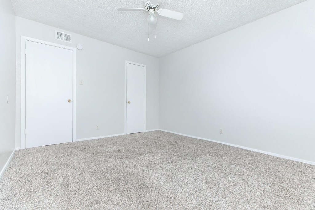 an empty living room with white walls and a ceiling fan