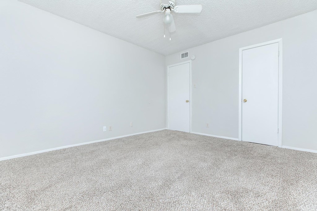 an empty room with a ceiling fan and white walls