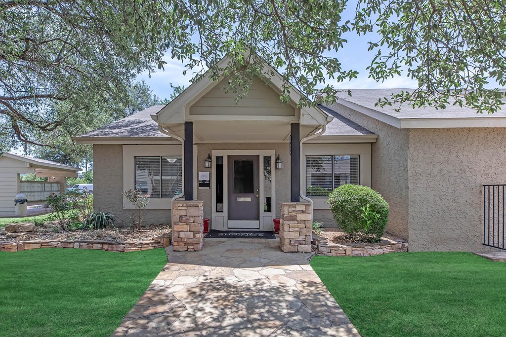 the front of a house with a walkway and grass