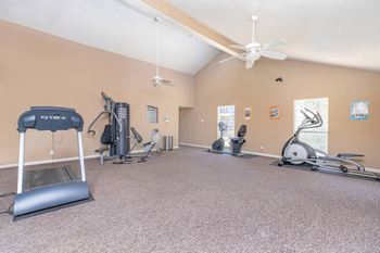 a gym with exercise machines and a ceiling fan
