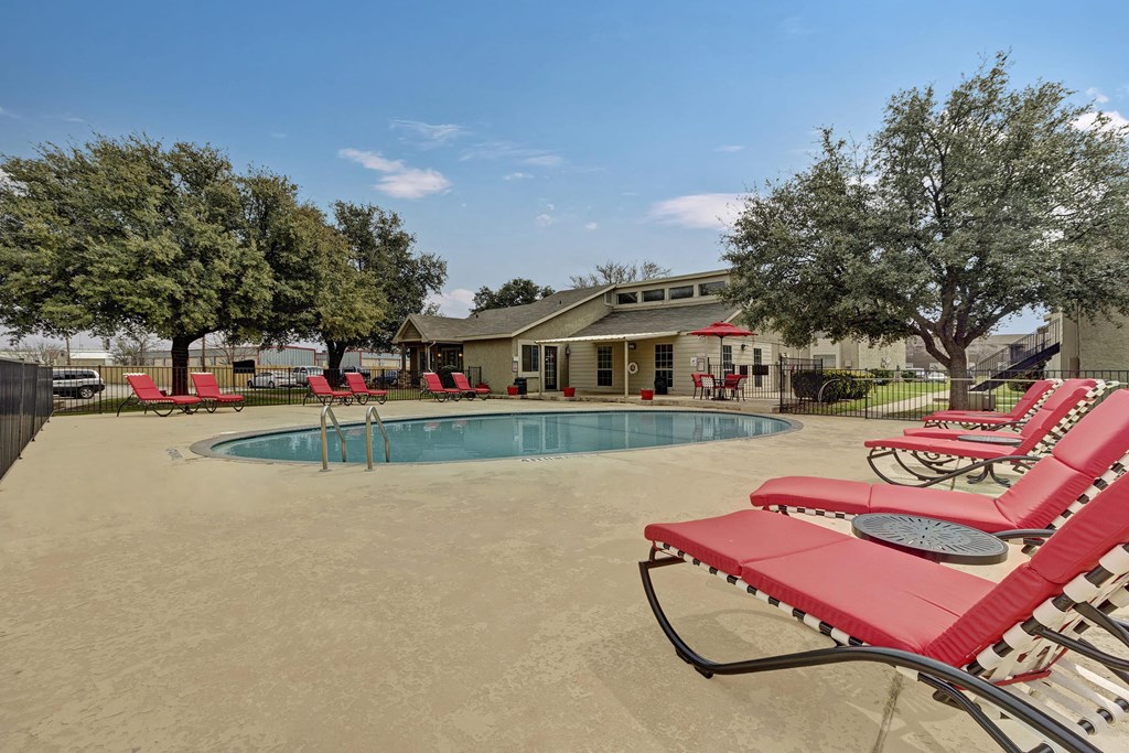 a pool with red chairs and a building in the background