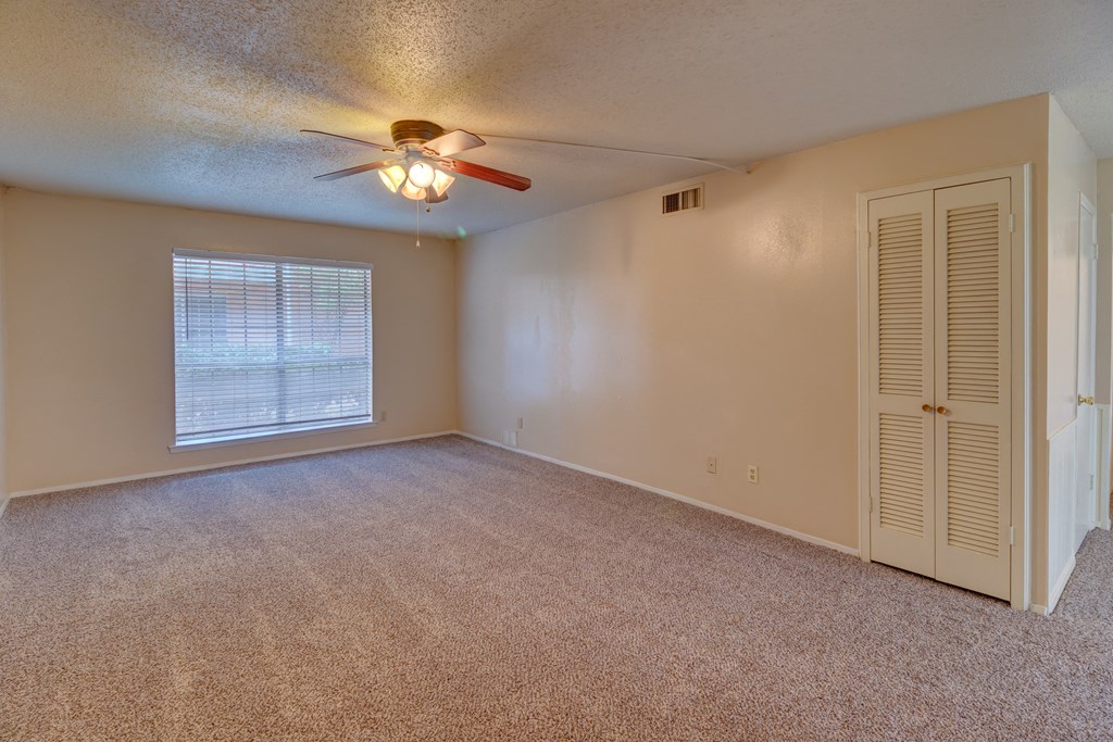 an empty living room with a ceiling fan and a window