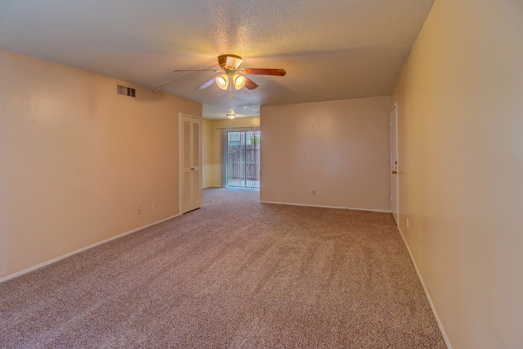 an empty living room with carpet and a ceiling fan
