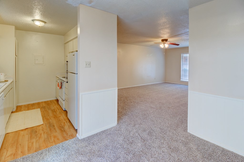 an empty kitchen and living room with a ceiling fan