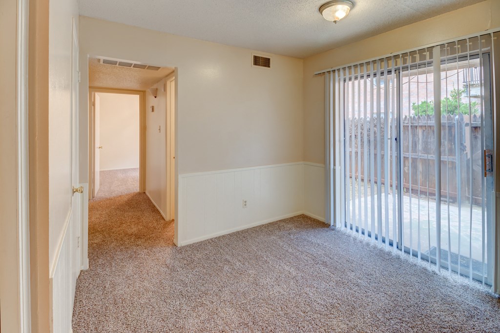 an empty living room with a sliding glass door to a patio