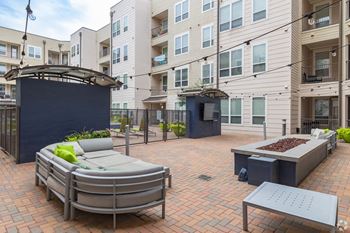 a patio with furniture and a fire pit in front of an apartment building