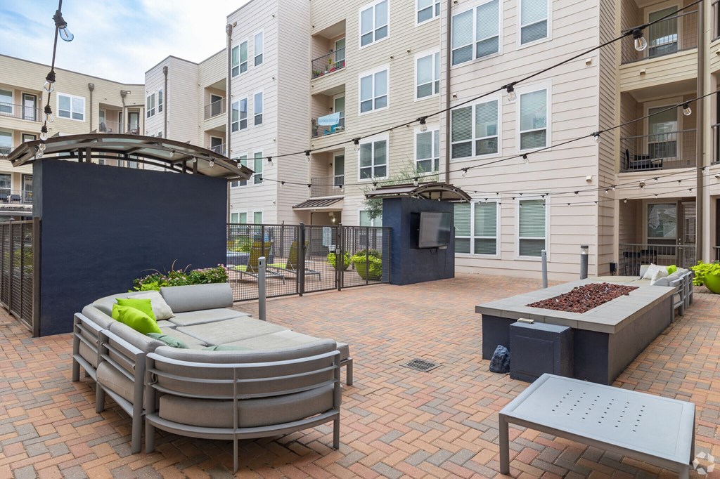 a patio with furniture and a fire pit in front of an apartment building