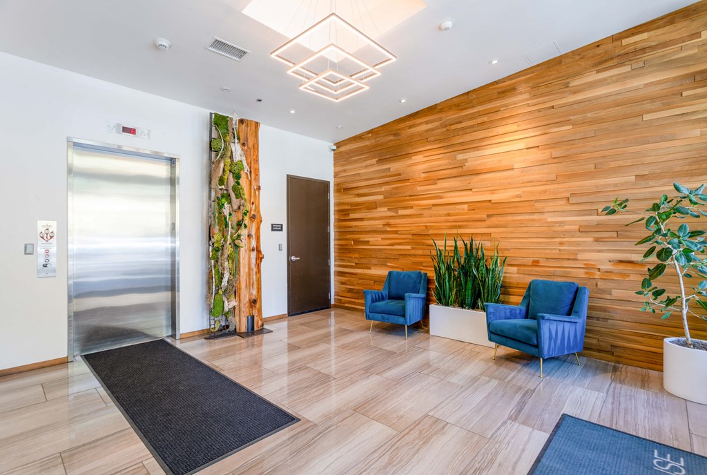 a lobby with blue chairs and a wooden wall and an elevator door door