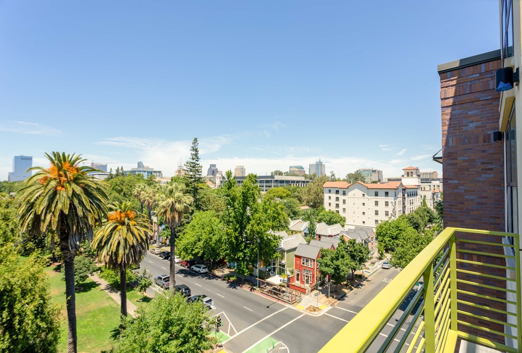a view of the city from a balcony of an apartment with trees