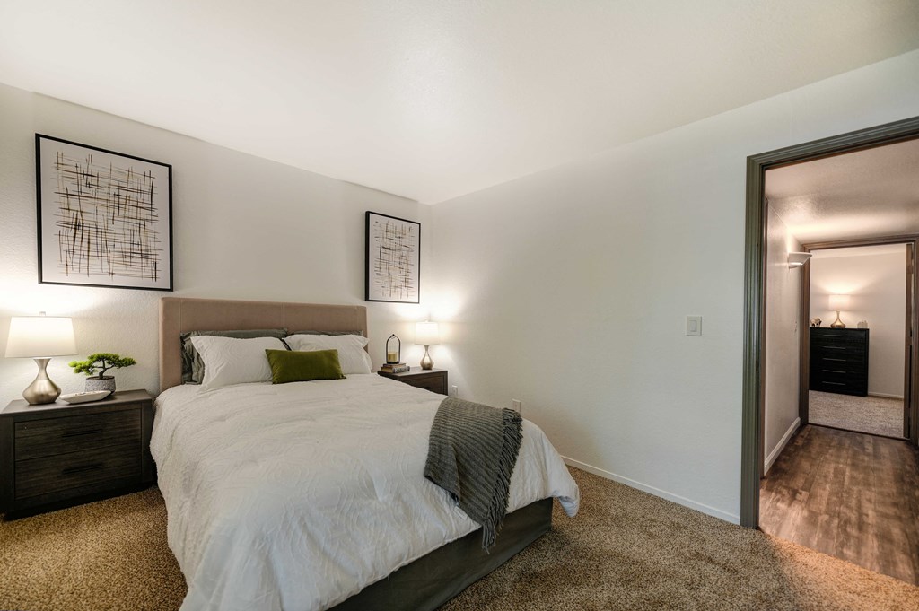 A bedroom with a large bed and two nightstands with lamps.