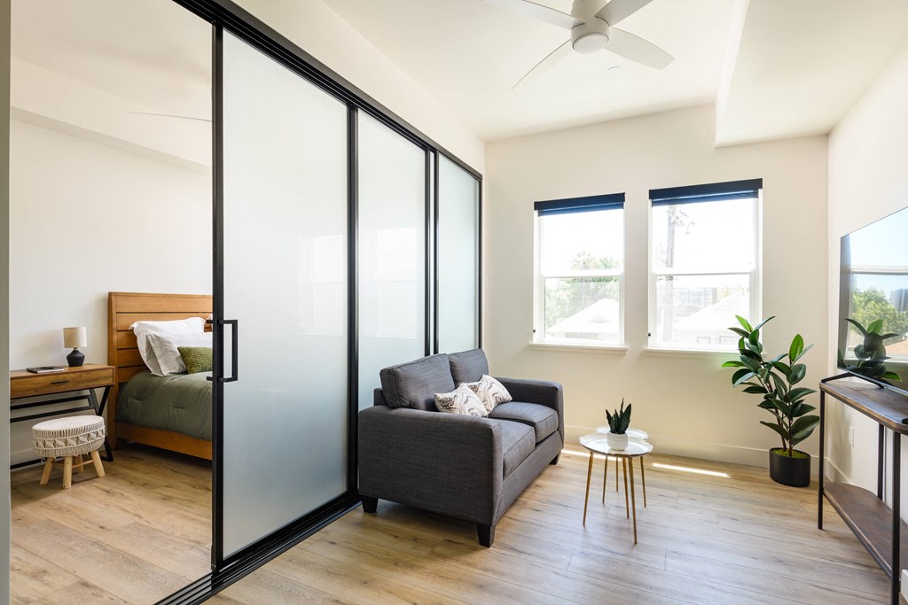 a living room with a couch and a chair next to a bedroom