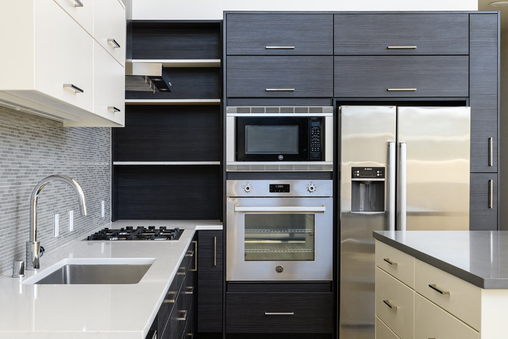 a kitchen with black and white cabinets and a stainless steel refrigerator