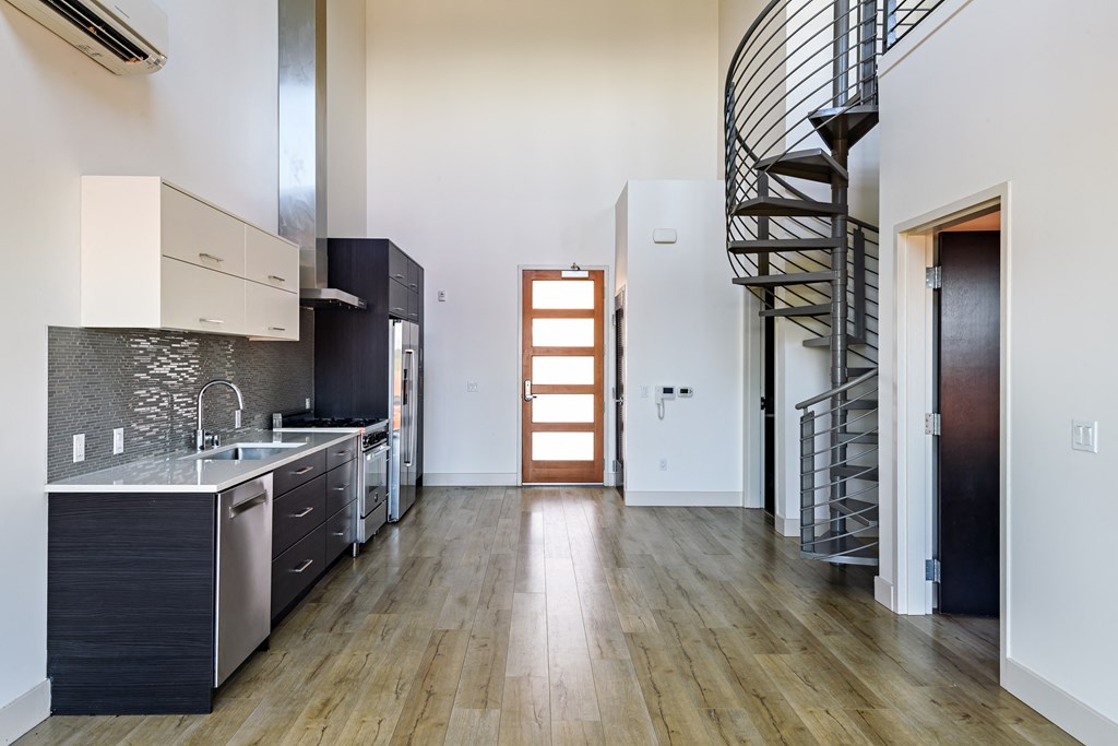 an open kitchen with a spiral stairway leading up to a loft