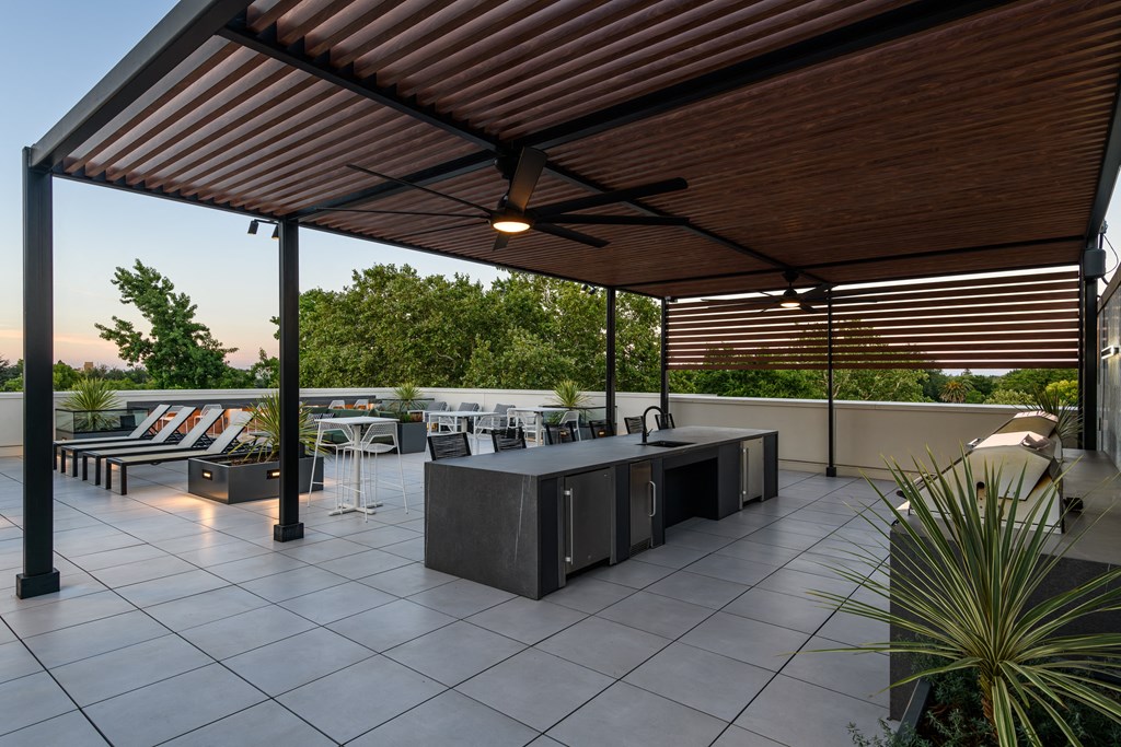 a covered patio with a bar and dining area on a roof