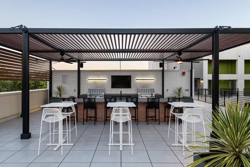 an outdoor BBQ patio with tables and chairs and a television