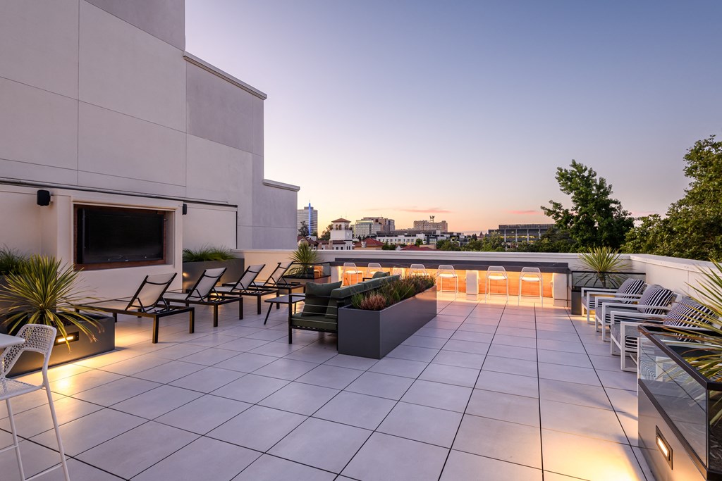 the rooftop terrace of a building with chairs and a television