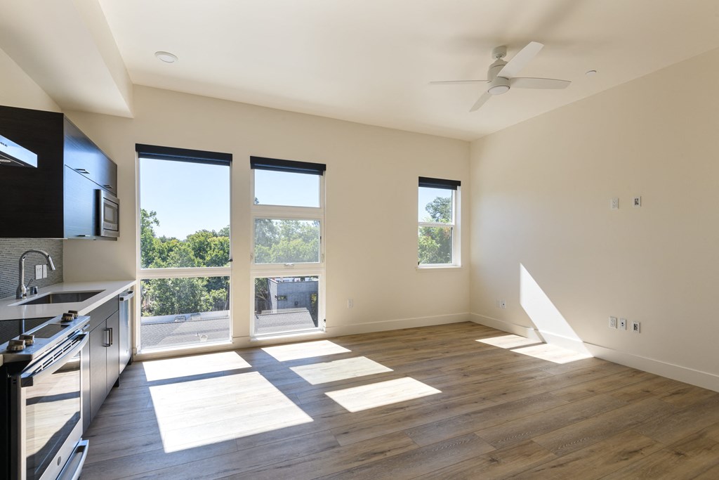 a living room with a large window and a kitchen