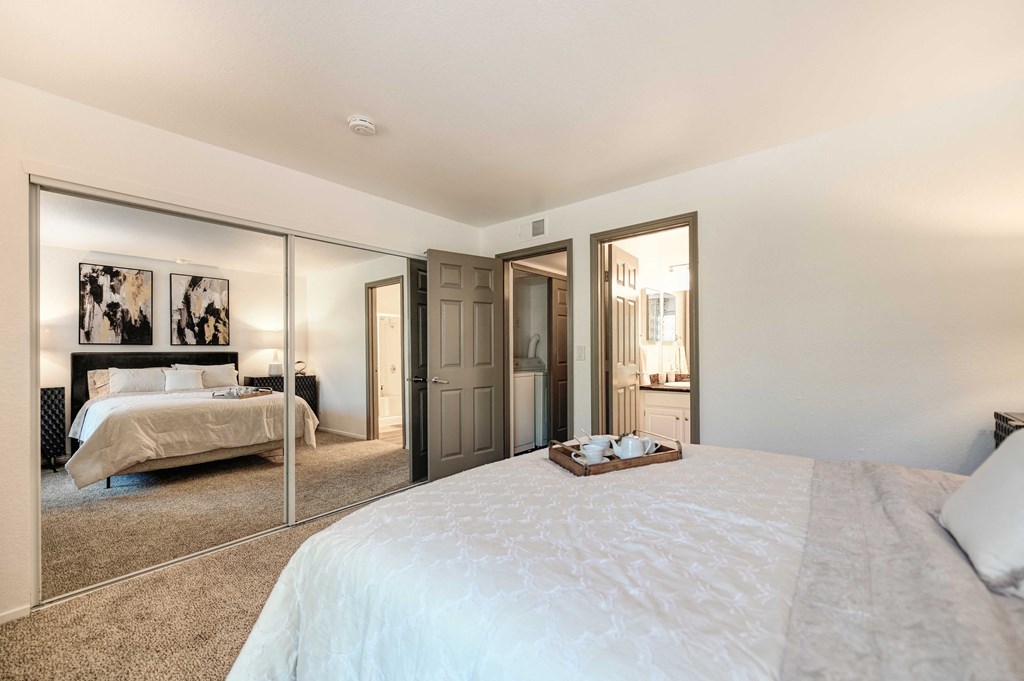 A bedroom with a large bed and a mirrored wall.