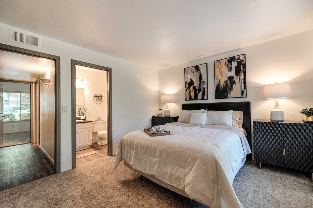 A bedroom with a large bed and a painting on the wall.