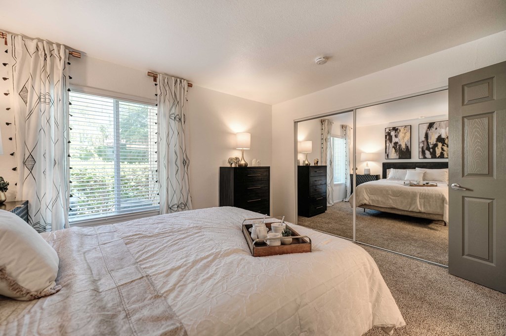 A bedroom with a large bed and a mirrored wall.