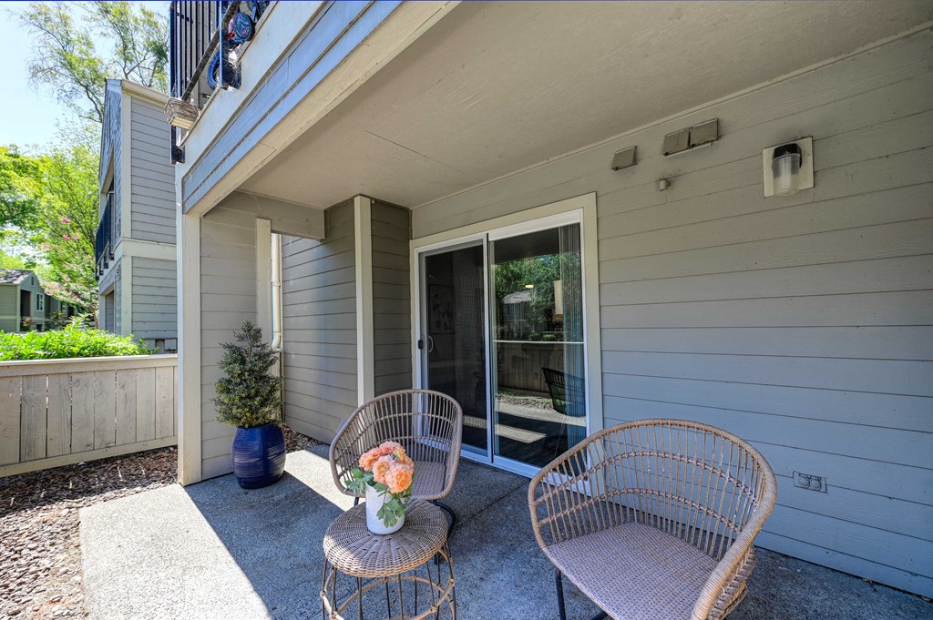 A patio with a chair and a vase of flowers.