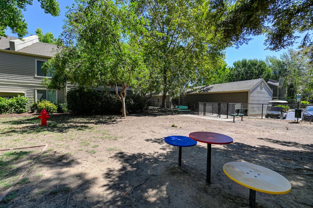 A playground with a red fire hydrant and a fence in the background.