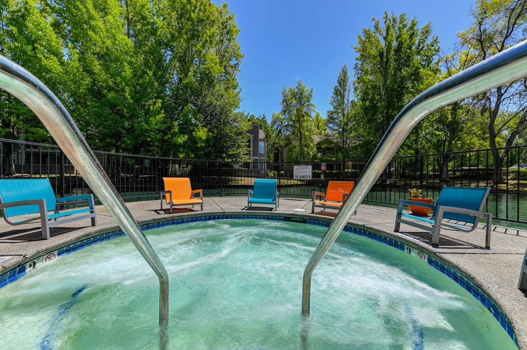 A hot tub with blue and orange chairs in a sunny outdoor setting.