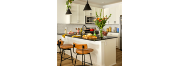 A kitchen with a black counter top and white cabinets.