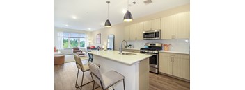 A kitchen with a white counter top and wooden floors.